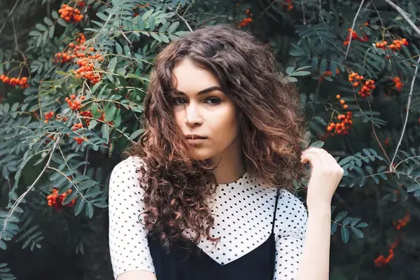 Young woman of mixed ethnicity with thick wavy hair that's been balayaged.