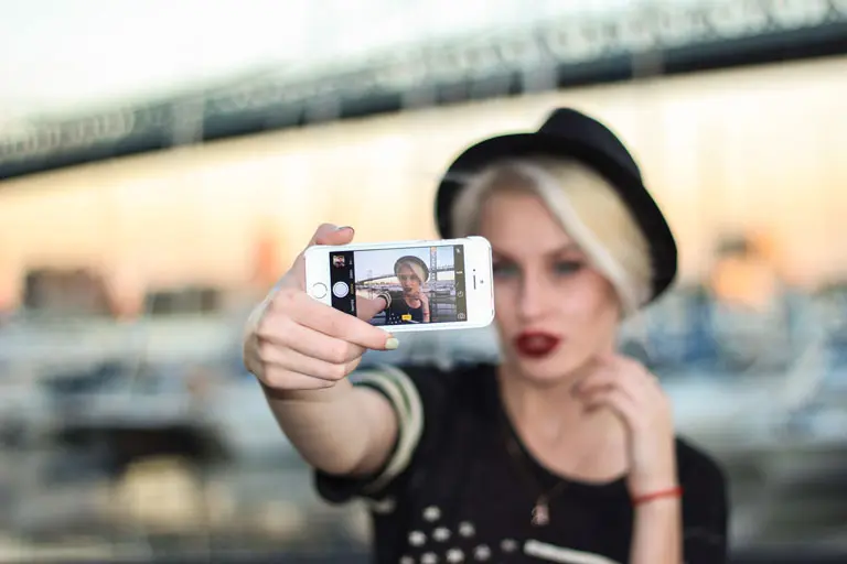 Young trendy woman with short hair, wearing a Fedora, taking a selfie